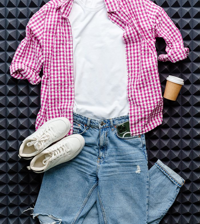 Casual clothes jeans, shirt, shoes on gray background top view flat lay